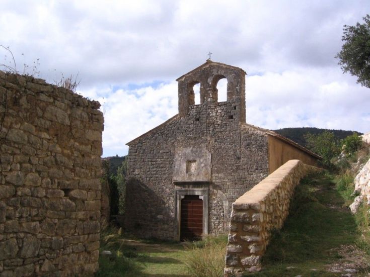 Une église en pierre située dans le village de Gabbio, entourée de végétation luxuriante.