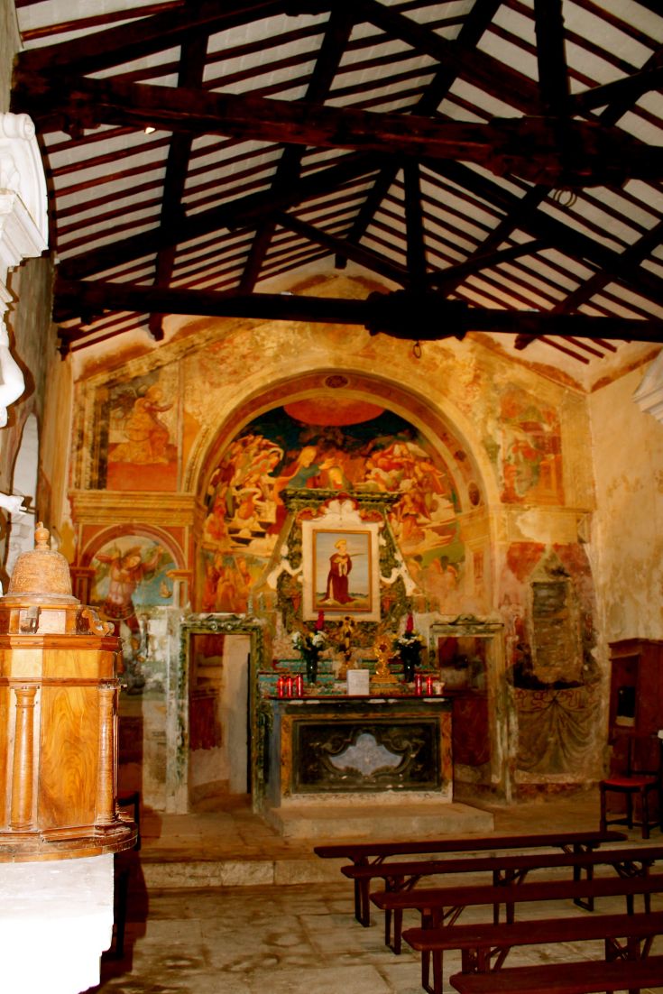 Intérieur d'une église historique avec des fresques et un autel décoré.