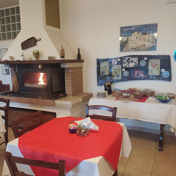 A well-furnished breakfast room with a fireplace and tables, perfect for enjoying an Italian breakfast.
