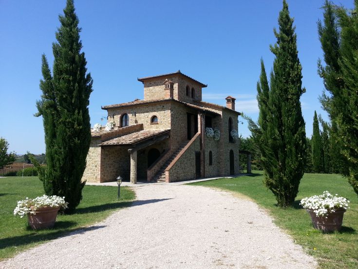La casa in pietra si trova circondata da vigneti e cipressi, creando un ambiente tranquillo e accogliente.