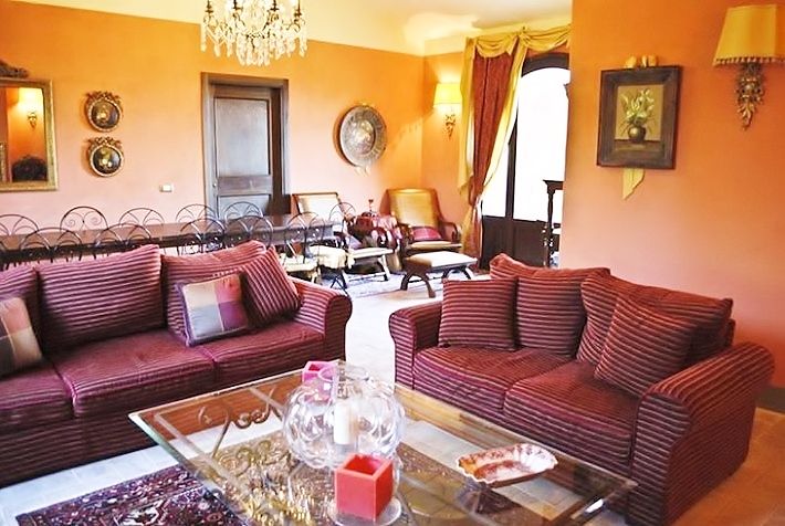 Casa in pietra immersa tra vigne e cipressi, con piscina e tessuti colorati, crea un'atmosfera suggestiva sul Lago Trasimeno.