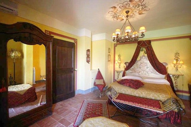 Camera semplice con letti a baldacchino, arredamento sobrio e tonalità calde. Spazio accogliente e rilassato.