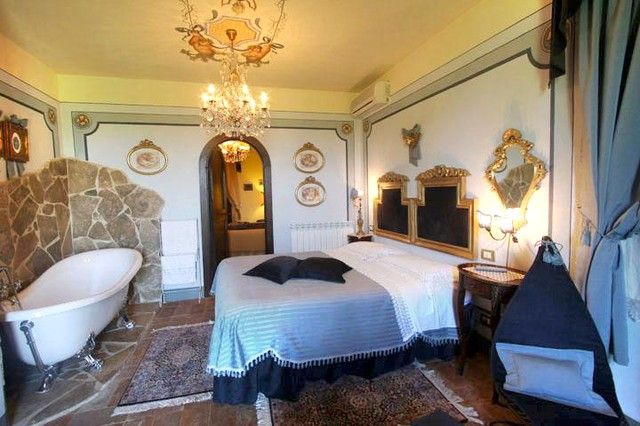 Camera da letto con letti a baldacchino e vasca, caratterizzata da elementi decorativi in stile classico.