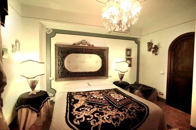 Camera con letto a baldacchino, arredamenti semplici e un lampadario che aggiunge una luce gradevole.