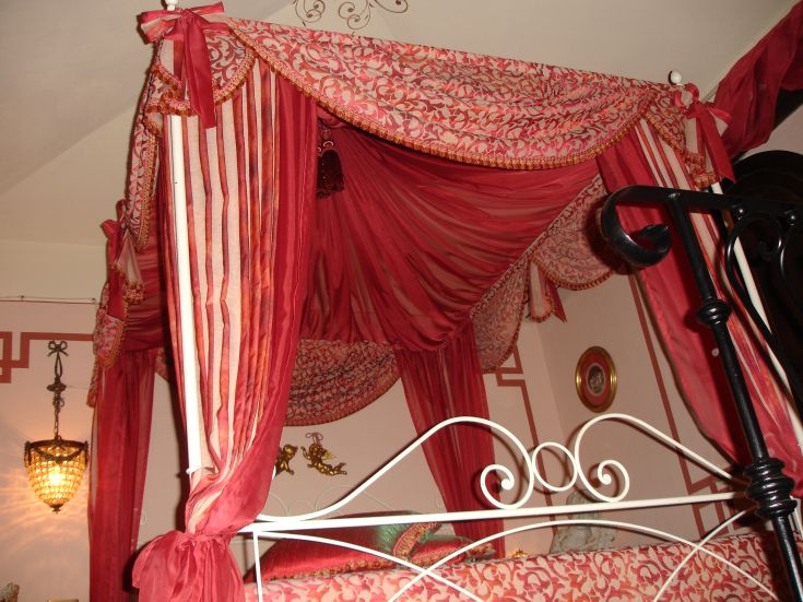 Una camera semplice con un letto a baldacchino dai toni caldi e tessuti morbidi.