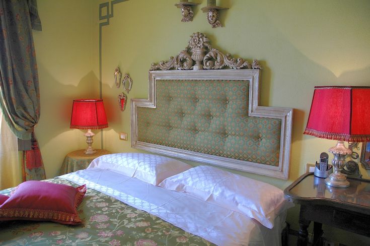 Interno di una camera con letti a baldacchino, decorazioni semplici e illuminazione delicata.