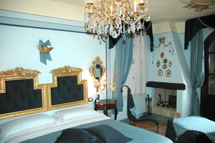 Camera sobria con un lampadario classico e decorazioni blu, adatta per un soggiorno confortevole.