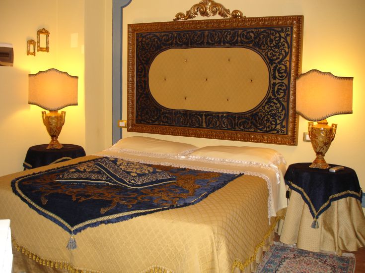 Camera accogliente con letto semplice, lampade dorate e tende in tessuto.