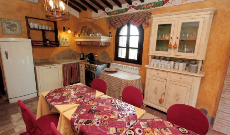 Cucina calda con arredamento semplice e tavoli variopinti, perfetta per convivialità tra familiari e amici.