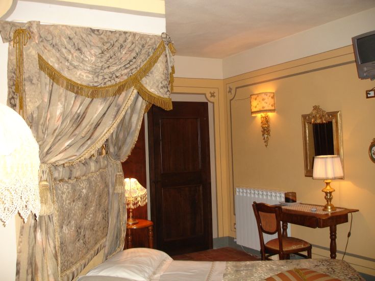 Camera confortevole con letti a baldacchino, illuminata da lampade e con tende eleganti.