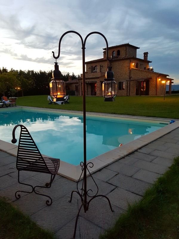 La villa in pietra si specchia nella piscina, immersa in un'atmosfera tranquilla al tramonto.