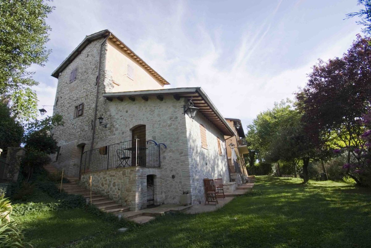 An ancient farmhouse surrounded by greenery, featuring a garden, pool, and independent apartments.