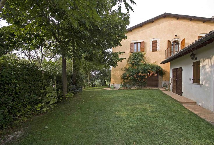 Un tipico casale umbro dell'Ottocento con un giardino curato e varie sistemazioni per gli ospiti.