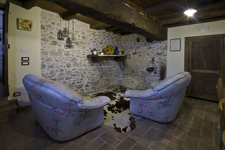 Spazio salotto confortevole con divani e pavimentazione in pietra, adatto per momenti di relax.