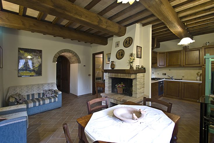 Spazio intimo con area living, cucina semplice e camino, caratteristico dello stile umbro.