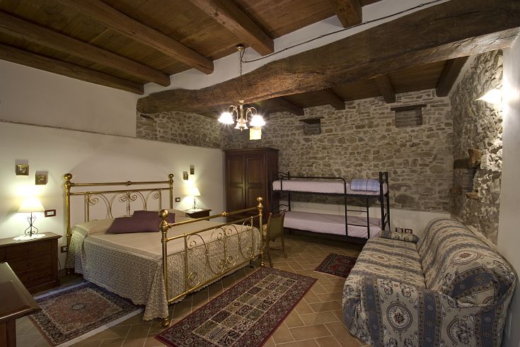Camera rustica con letto matrimoniale e un letto a castello, ambiente semplice e rilassante.