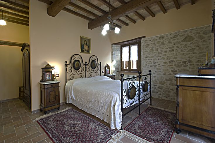 Camera semplice con letto in ferro e elementi rustici. Perfetta per un soggiorno tranquillo.