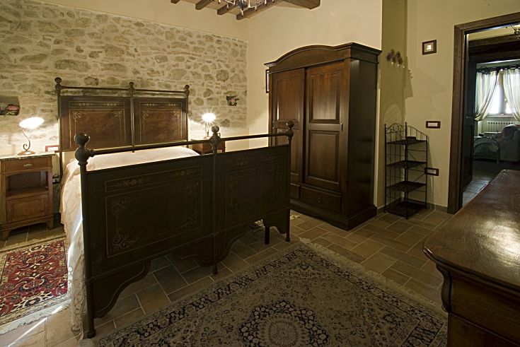 Camera accogliente con cucina in legno, letto in ferro battuto e particolari rustici, ideale per un soggiorno tranquillo.