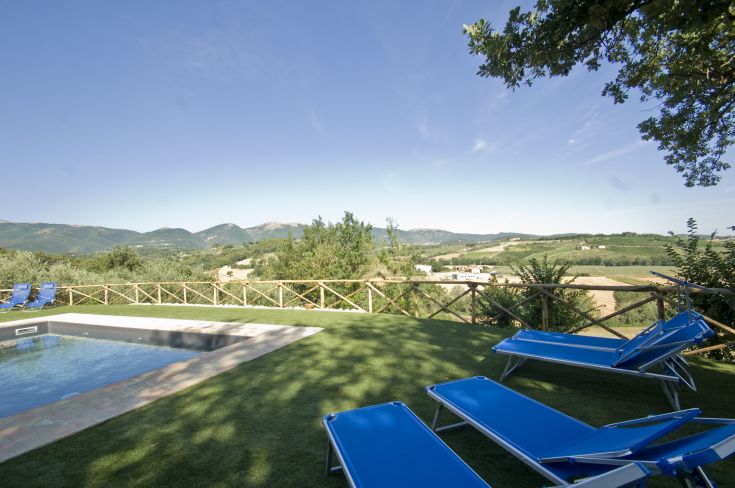 Una piscina con lettini immersi nel verde, circondati da dolci colline umbre.