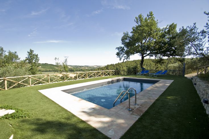 La piscina di un casale umbro circondata da un ampio spazio verde, perfetta per un momento di relax.