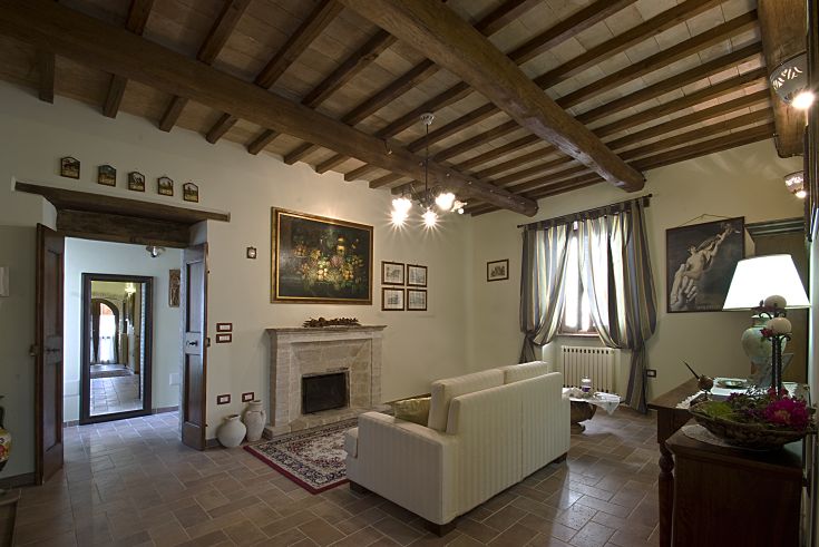 Soggiorno semplice con camino, travi in legno a vista e decorazioni per la casa.