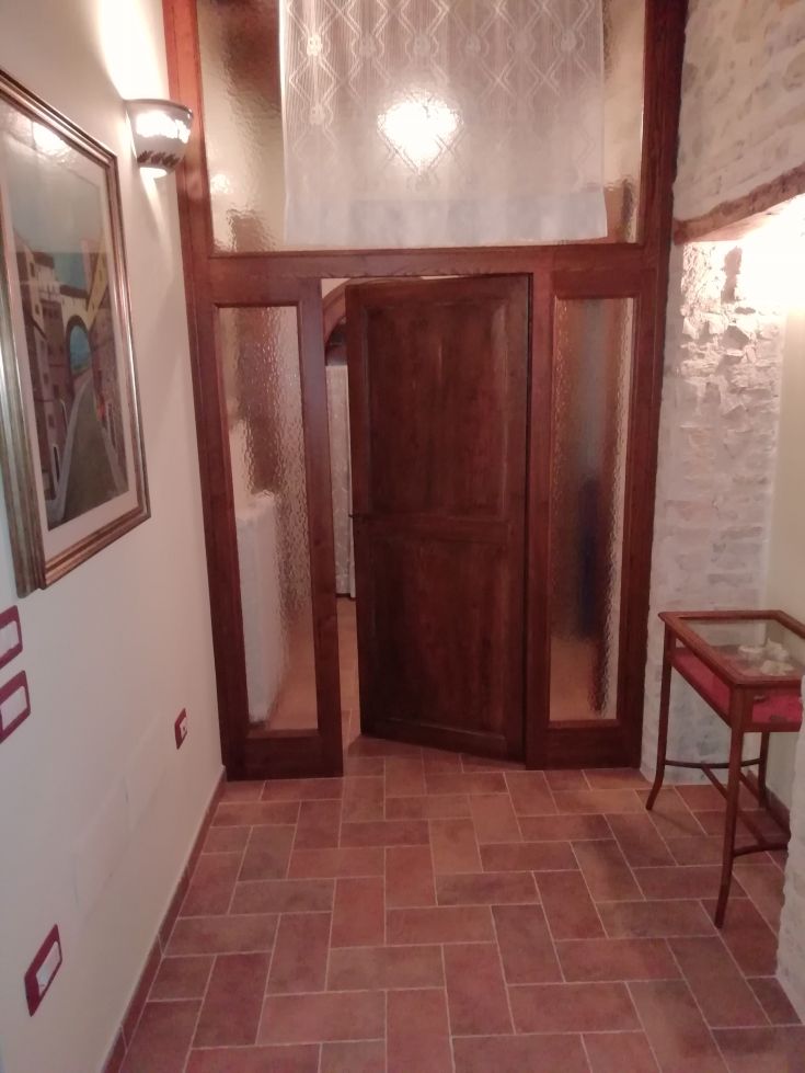 Ingresso di un casale con porta in legno e inserti in vetro, ristrutturato con attenzione ai dettagli.