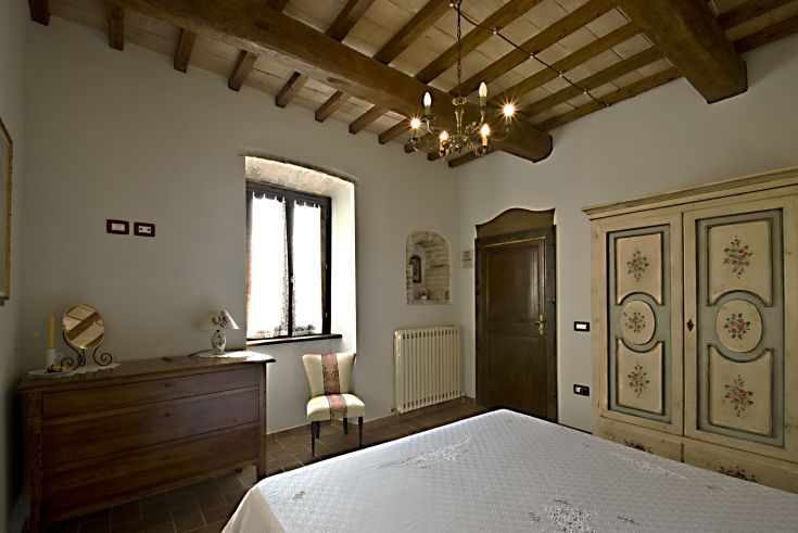 Camera accogliente con arredi rustici e panorama su un paesaggio collinare.