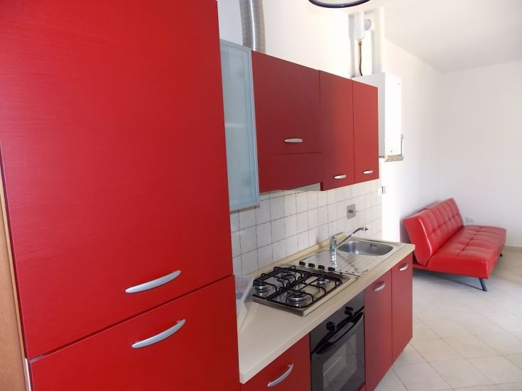 Moderne Küche mit roten Möbeln und einem gemütlichen Sofa, gut organisierten und einladenden Raum.