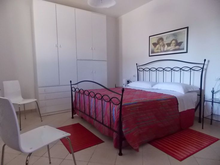 Helle Zimmer mit einem Doppelbett und praktischen Möbeln, ideal für Entspannungsmomente.