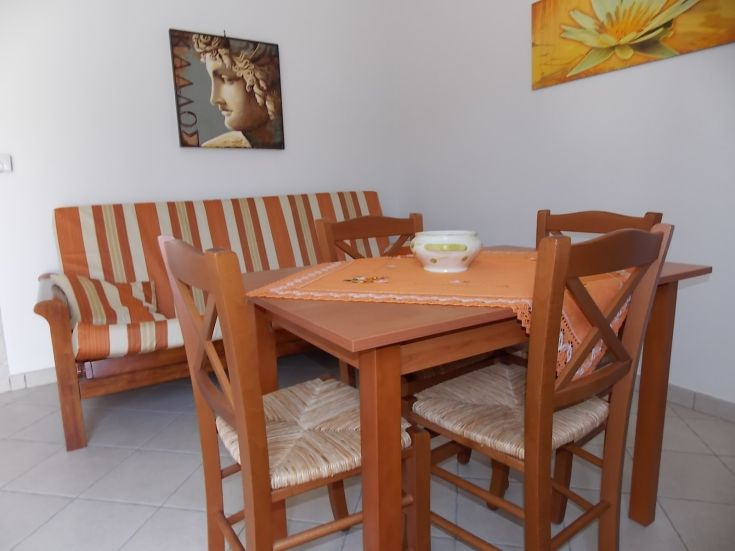 Einfaches Wohnzimmer mit einem Holztisch und einer Bank, ideal für Entspannungsmomente.