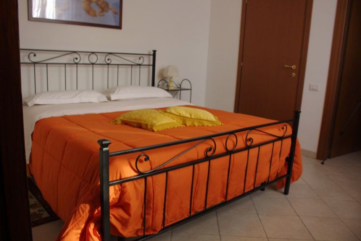 Ein einfaches Zimmer mit einem Bett und lebhaft gefärbter Bettwäsche, ideal für entspannende Momente.