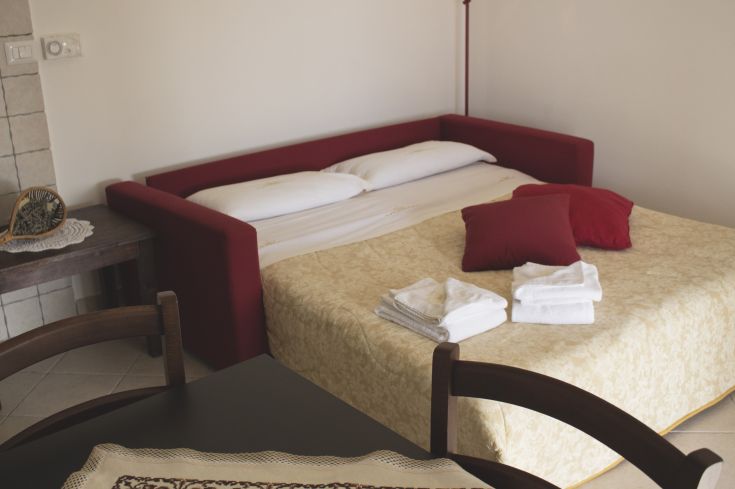 Eine gemütliche Umgebung mit einem Schlafsofa und frischen Laken, perfekt für einen ruhigen Aufenthalt.