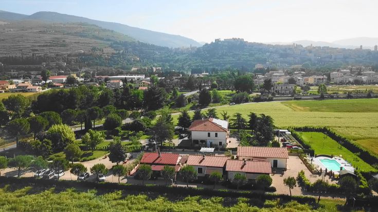 Panorama des Terra dei Santi Country House, gelegen in der umbrischen Landschaft, mit Pool und Bäumen.