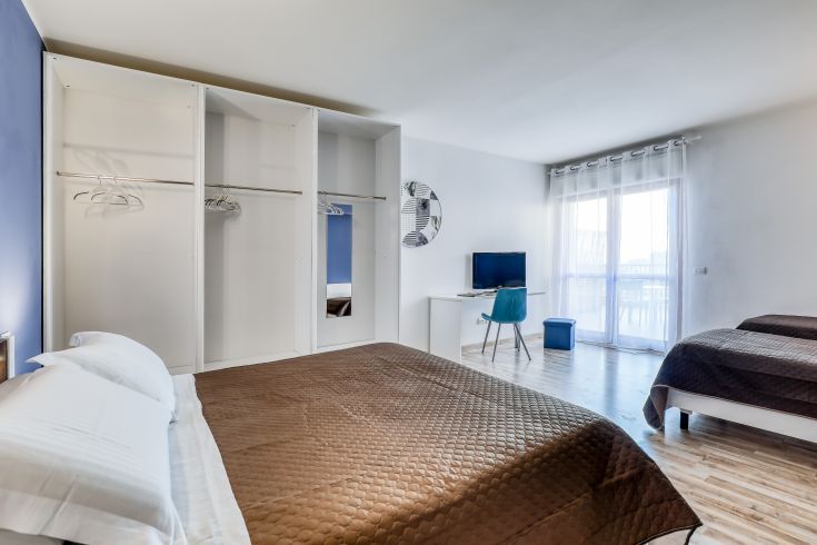 Camera moderna con letti singoli e panorama su un'area illuminata. Spazio accogliente e confortevole.