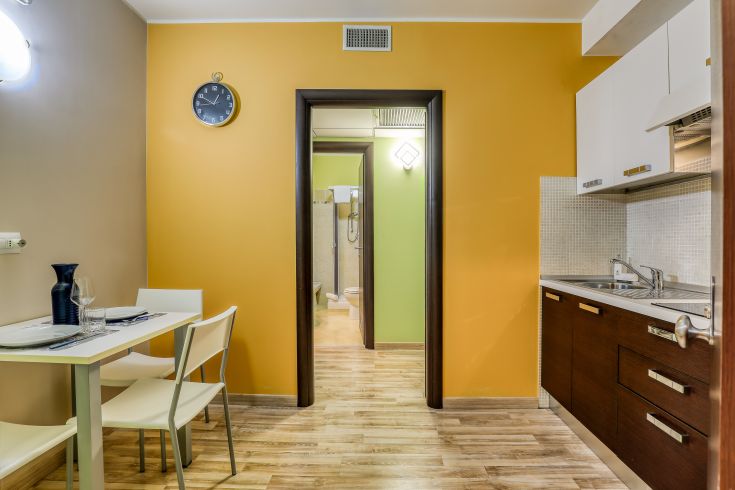 Interno di un palazzo moderno con cucina e area pranzo, arredato in tonalità calde e accoglienti.