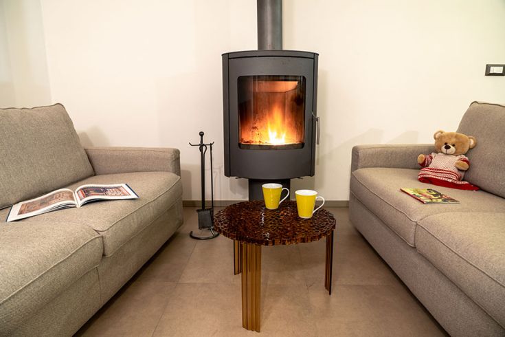 Ein gemütlicher Raum mit einem brennenden Kamin, weichen Armstühlen und einem gut arrangierten Tisch. Perfekt für entspannende Momente.