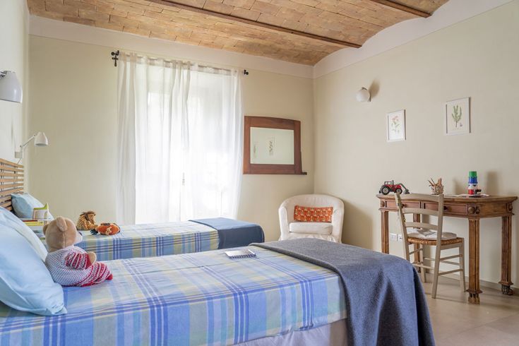 Ein einfaches Familienzimmer mit Einzelbetten, eingerichtet in warmen Tönen, ideal für Familien.