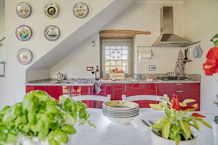 Einfach Küche mit roten Möbeln und Wanddekorationen. Helle und sehr komfortable Atmosphäre.
