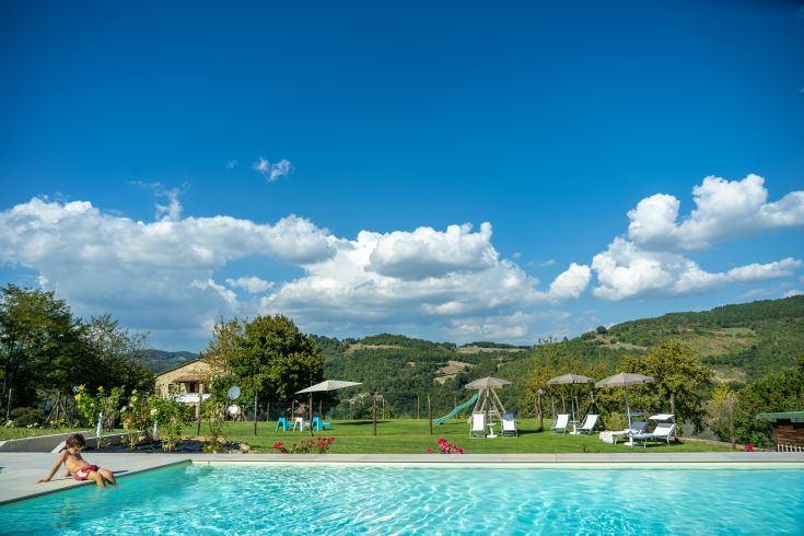 Schwimmbad im Agriturismo Montelovesco, umgeben von üppigem Grün typisch für die umbrische Landschaft.