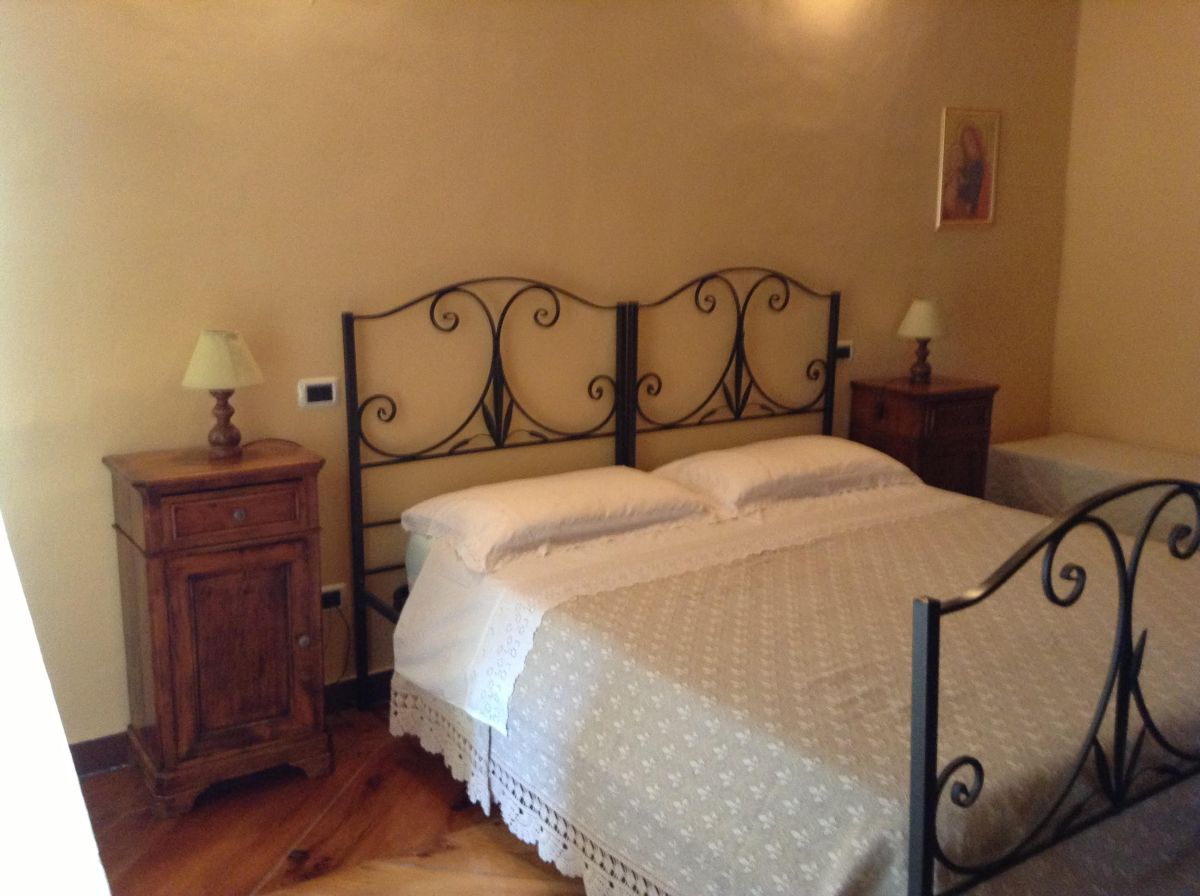 Una camera confortevole con un letto in ferro battuto e mobili in legno chiaro.