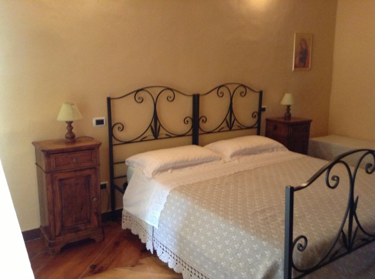 Una camera confortevole con un letto in ferro battuto e mobili in legno chiaro.