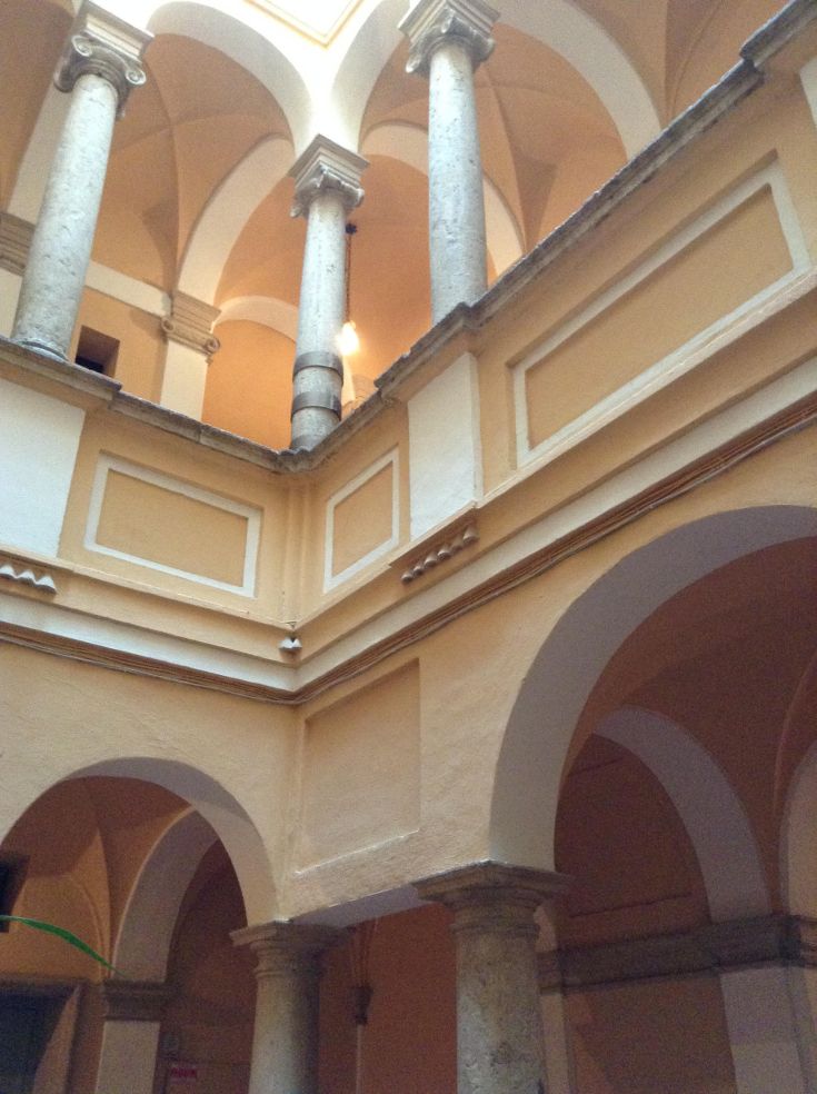 Interno di un palazzo storico con colonne e soffitti alti.
