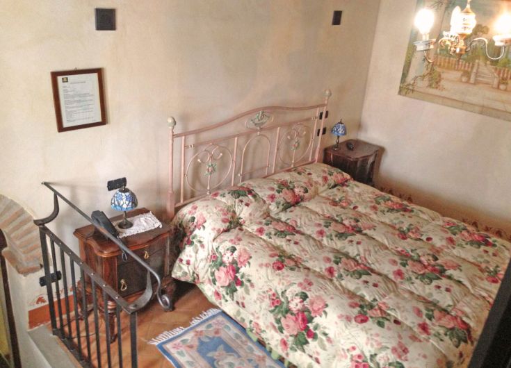 Chambre simple avec un lit double et des décorations florales, atmosphère rustique et tranquille.