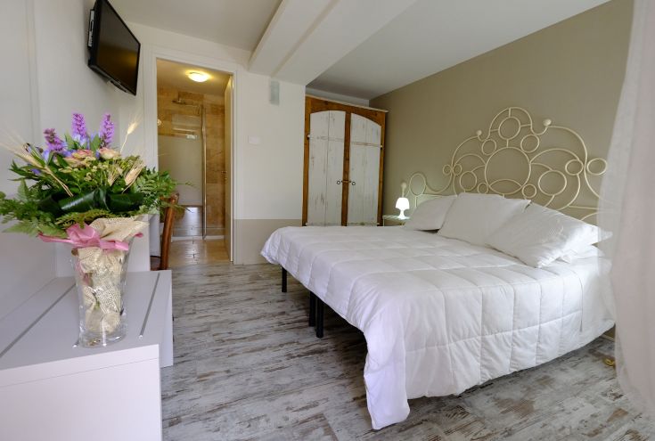 Einfaches Zimmer mit Doppelbett und Blumen-Dekorationen. Ideal für einen ruhigen Aufenthalt.