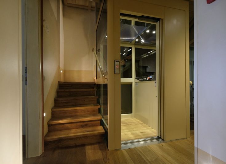 Innenraum eines Agritourismus mit hellen Wänden und einem Glasauszug neben einer Holztreppe.