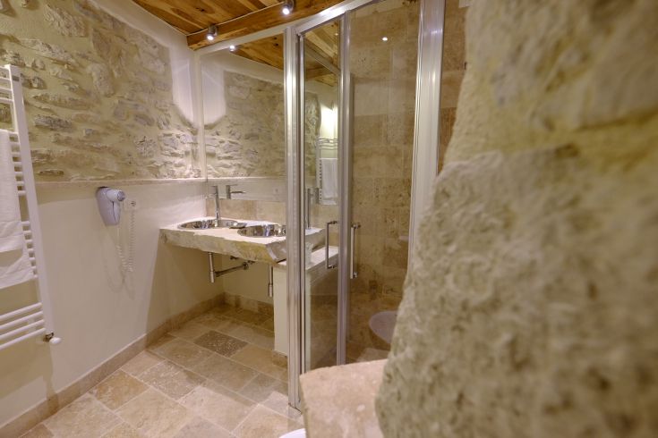 Einfaches Bad mit Steinwänden, Marmorspüle und funktionaler Dusche.