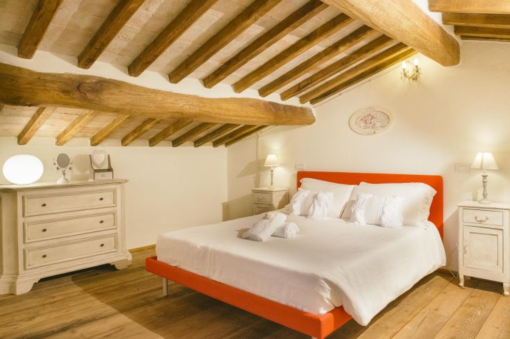 Cozy bedroom with wooden ceiling and simple furnishings. Ideal for relaxation moments.