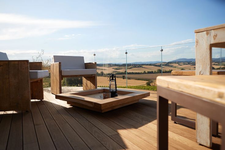 Outdoor terrace overlooking gentle hills, furnished with comfortable wooden furniture for a relaxing atmosphere.