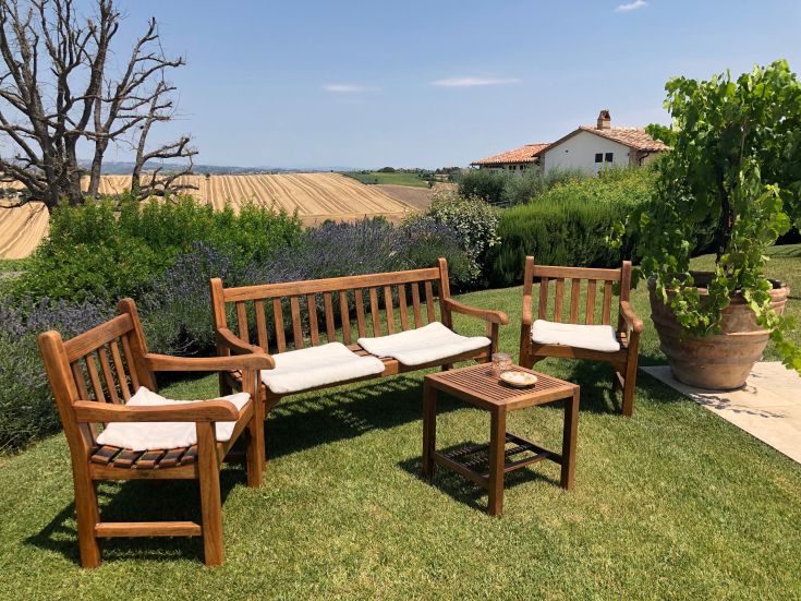 A peaceful corner in a well-kept garden, featuring wooden benches and a view of the surrounding greenery.