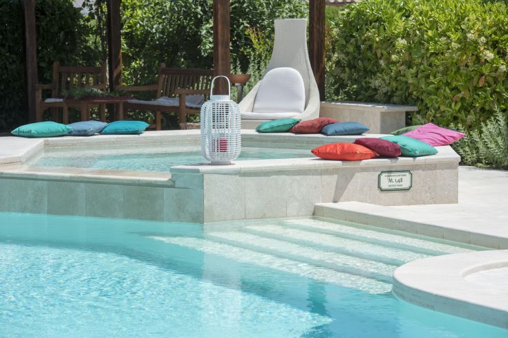 A pool surrounded by greenery, equipped with colorful cushions for comfort and relaxation.